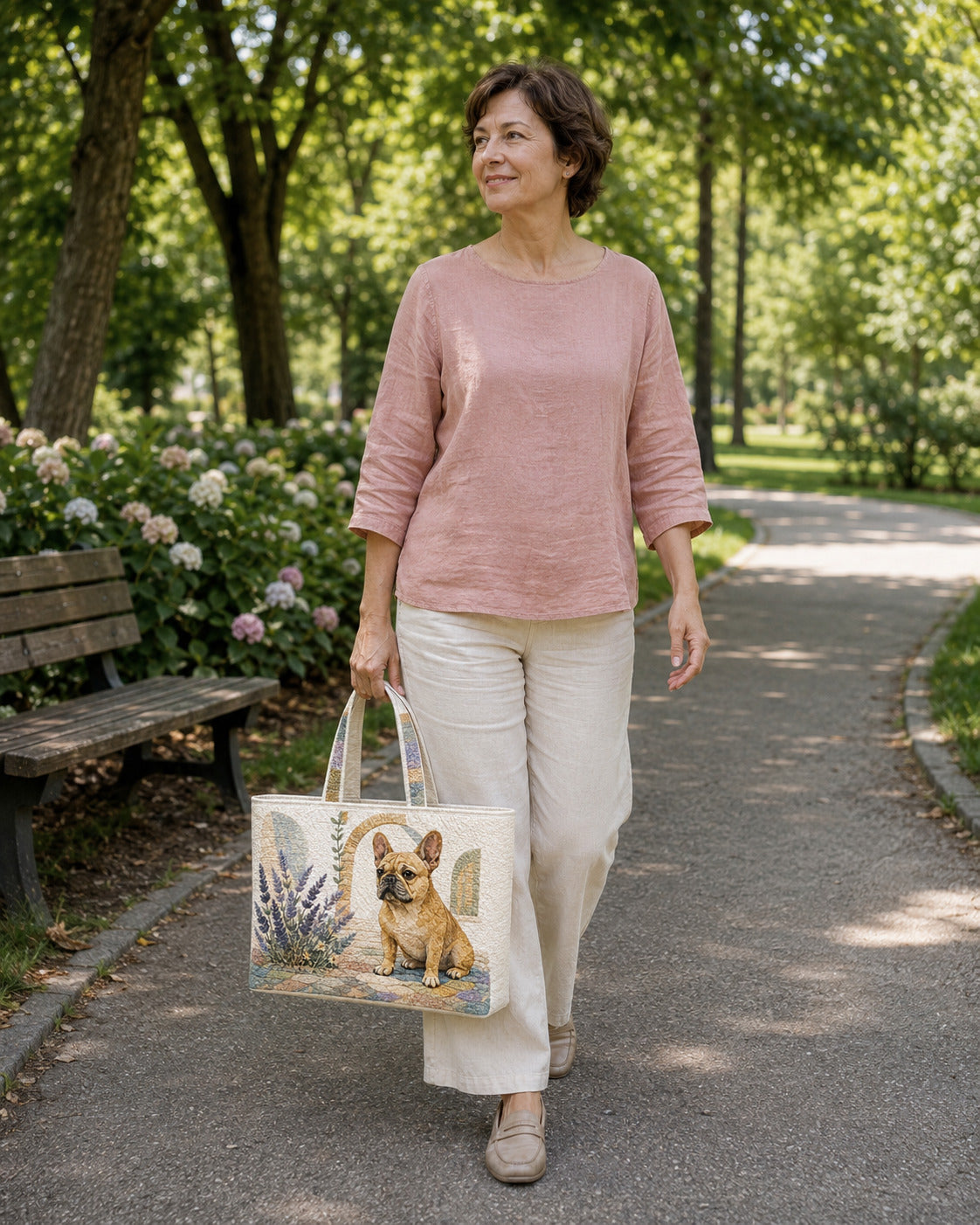 Woman carrying the French Bulldog Lavender Porch quilted tote along a garden walkway