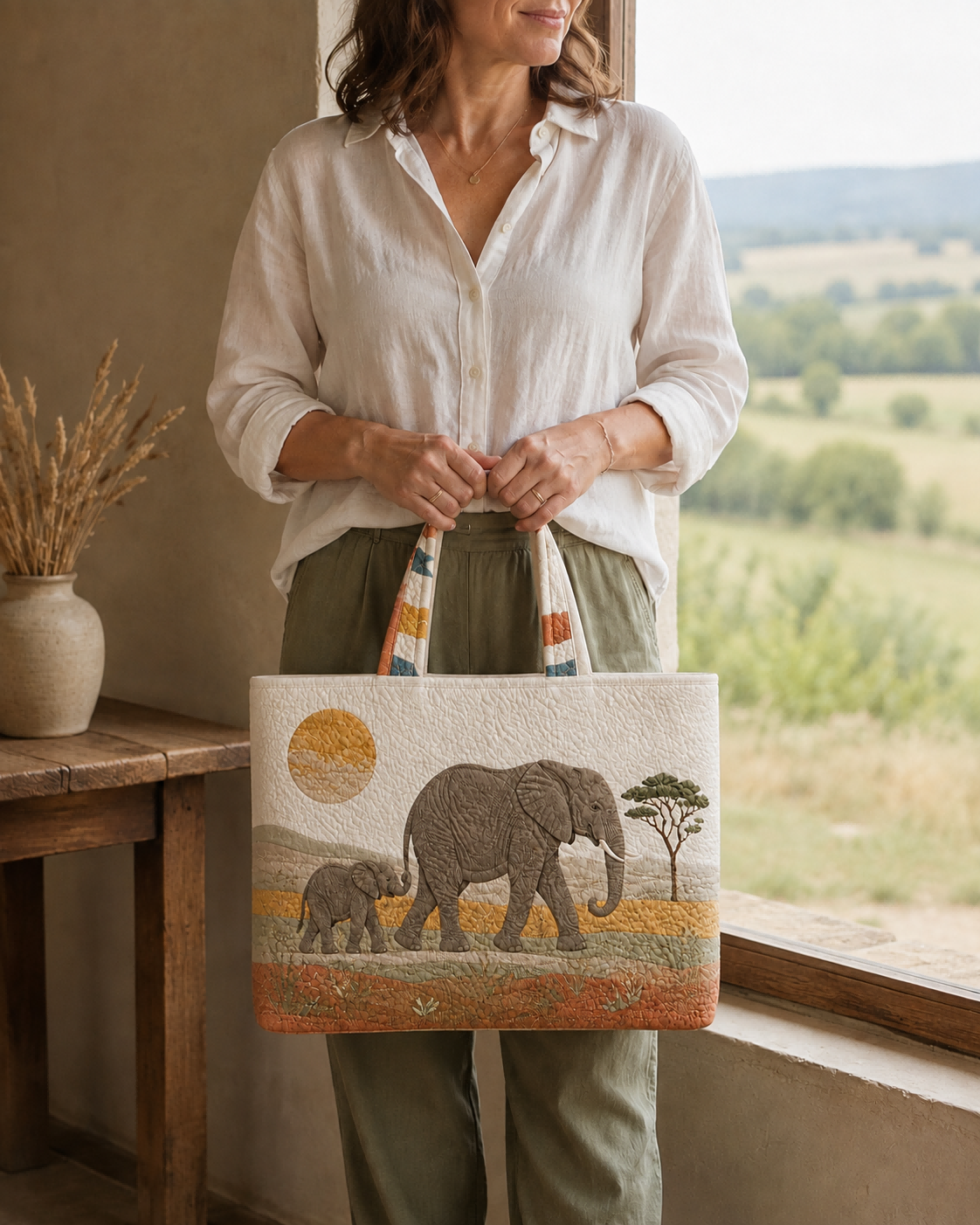 Woman holding the Elephant Dawn Passage quilted tote indoors beside a window